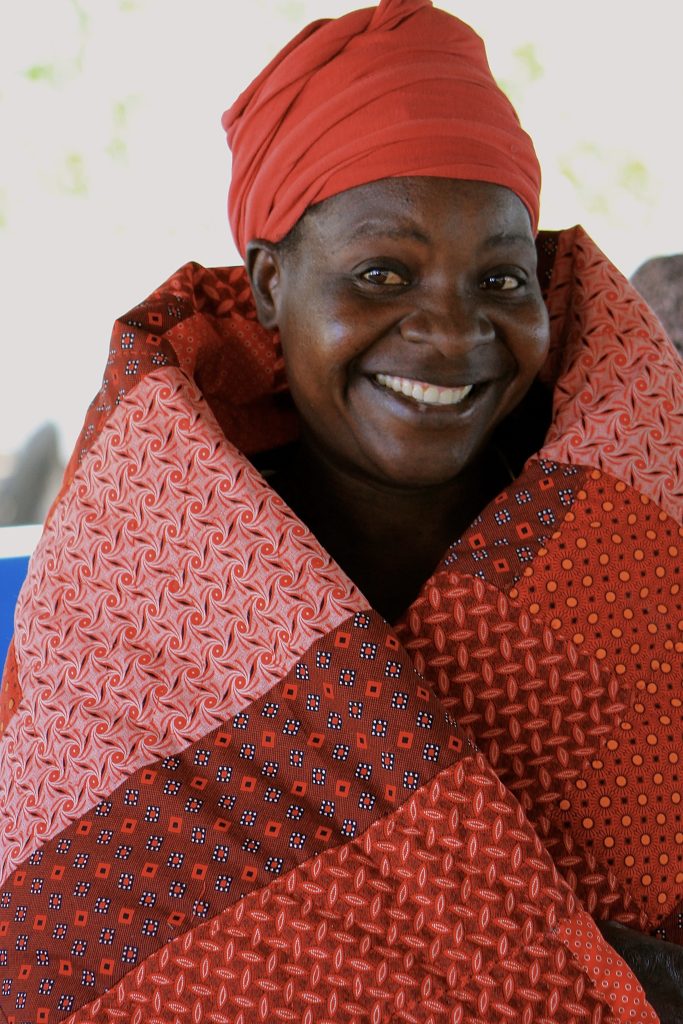 botswana woman wrapped in hand-sewn quilt made with german-print fabric